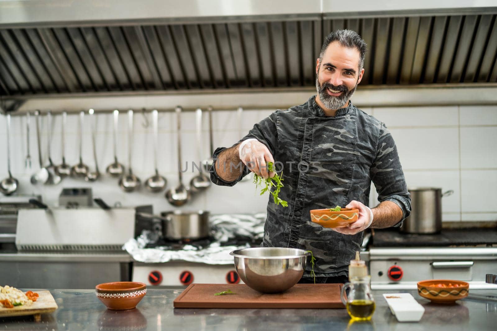 Professional cook is preparing meal in restaurant's kitchen. He is making salad.