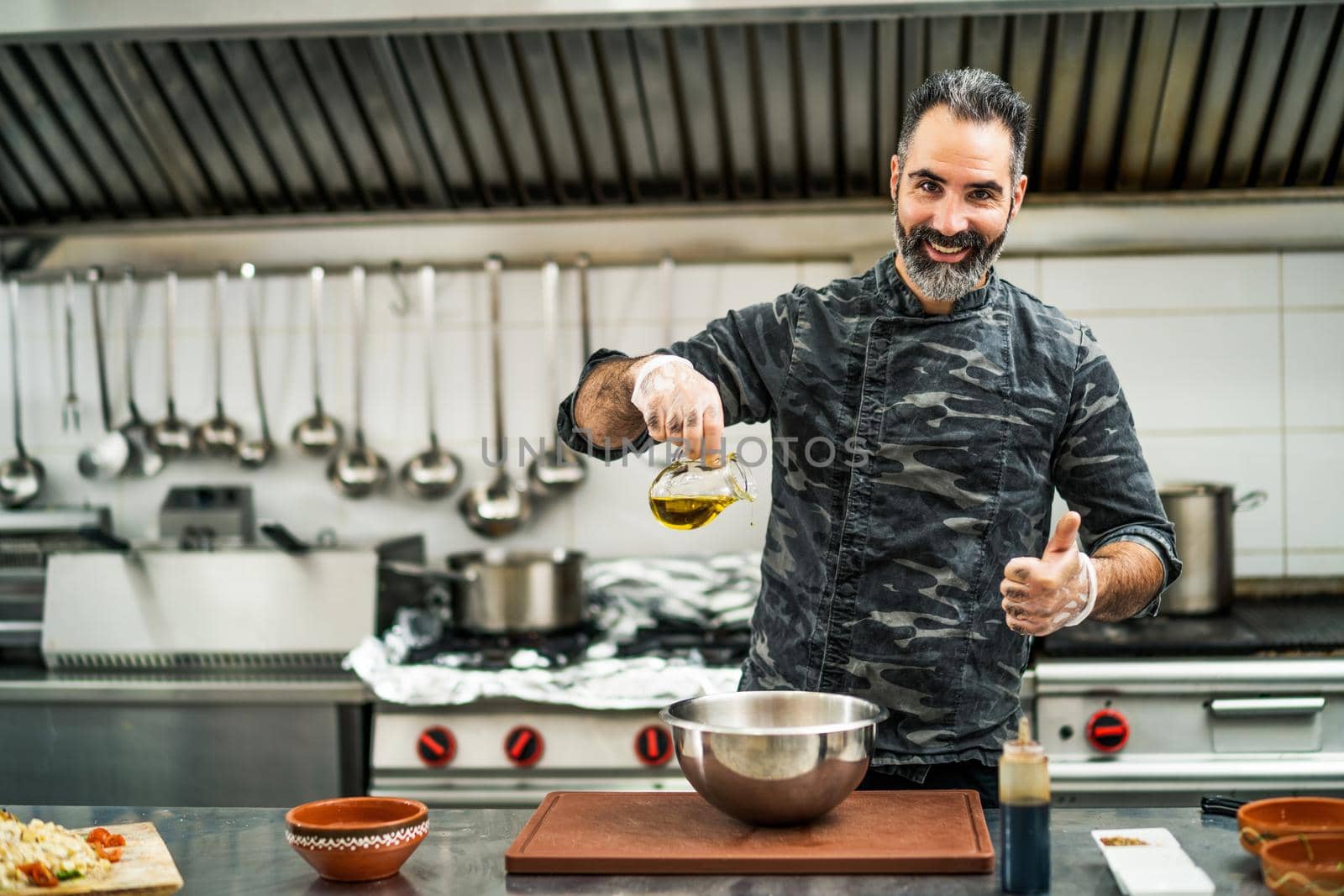 Professional cook is preparing meal in restaurant's kitchen. He is making salad.