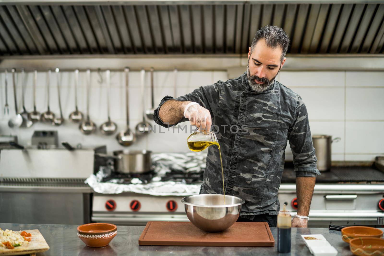 Professional cook is preparing meal in restaurant's kitchen. He is making salad.