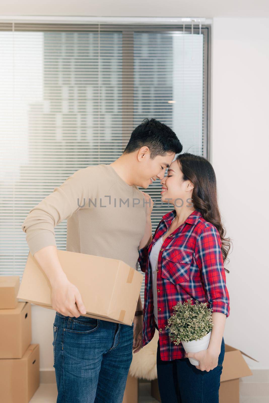 Happy young couple moving into new apartment with packaging boxes