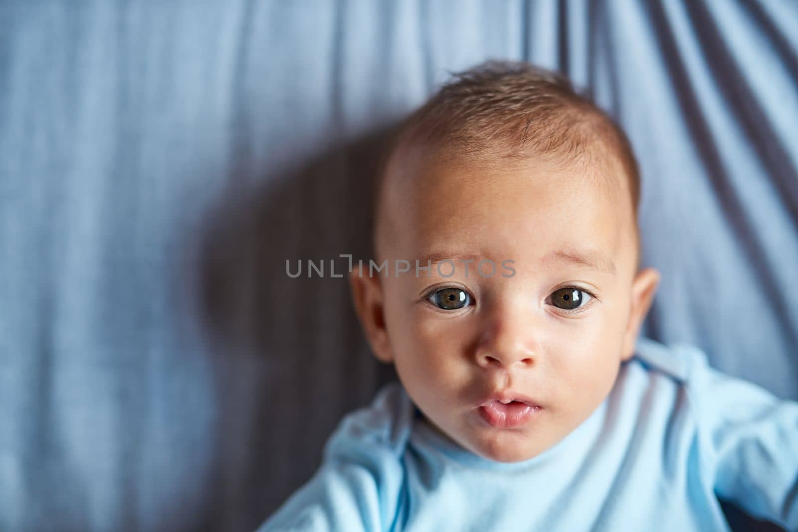 The sweetest face in the world. Portrait of an adorable baby boy laying on the bed at home