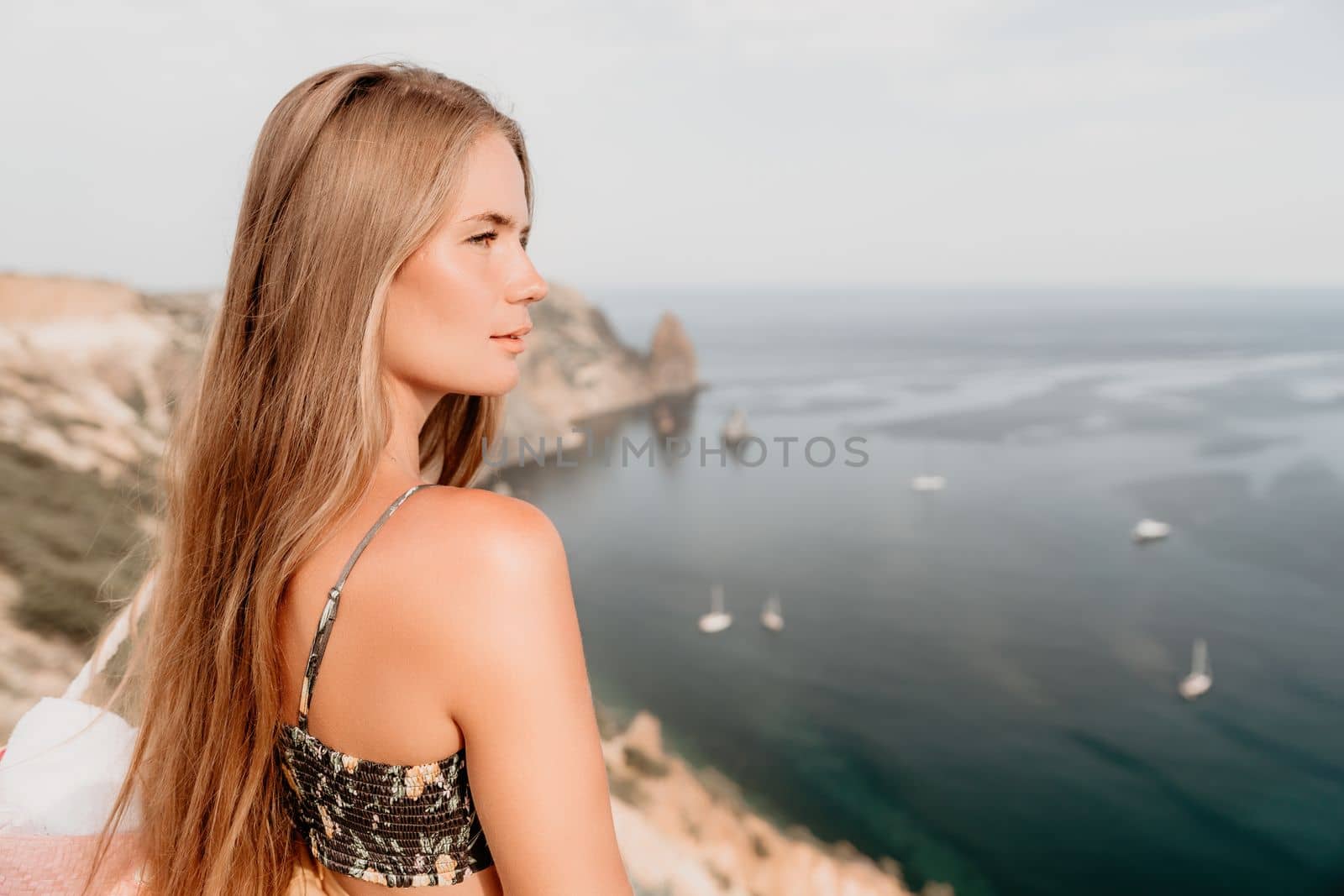 Woman travel sea. Happy tourist taking picture outdoors for memories. Woman traveler looks at the edge of the cliff on the sea bay of mountains, sharing travel adventure journey.