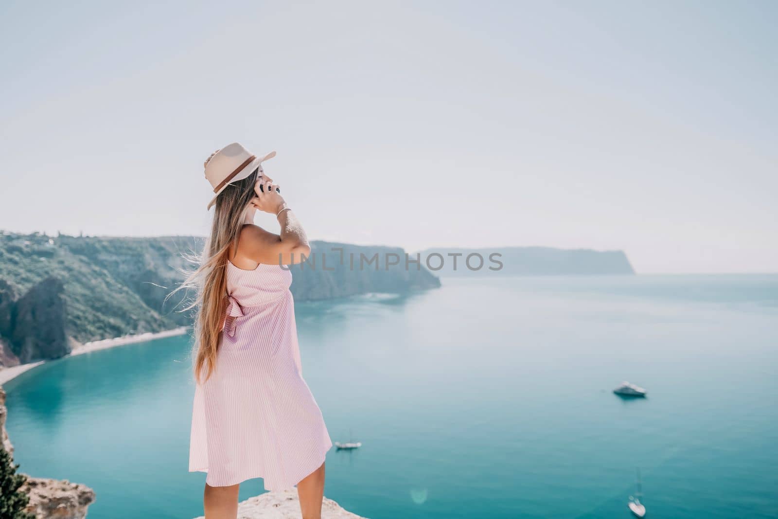 Woman sea laptop. Business woman in yellow hat freelancer with laptop working over blue sea beach. Girl relieves stress from work. Freelance, digital nomad, travel and holidays concept by panophotograph