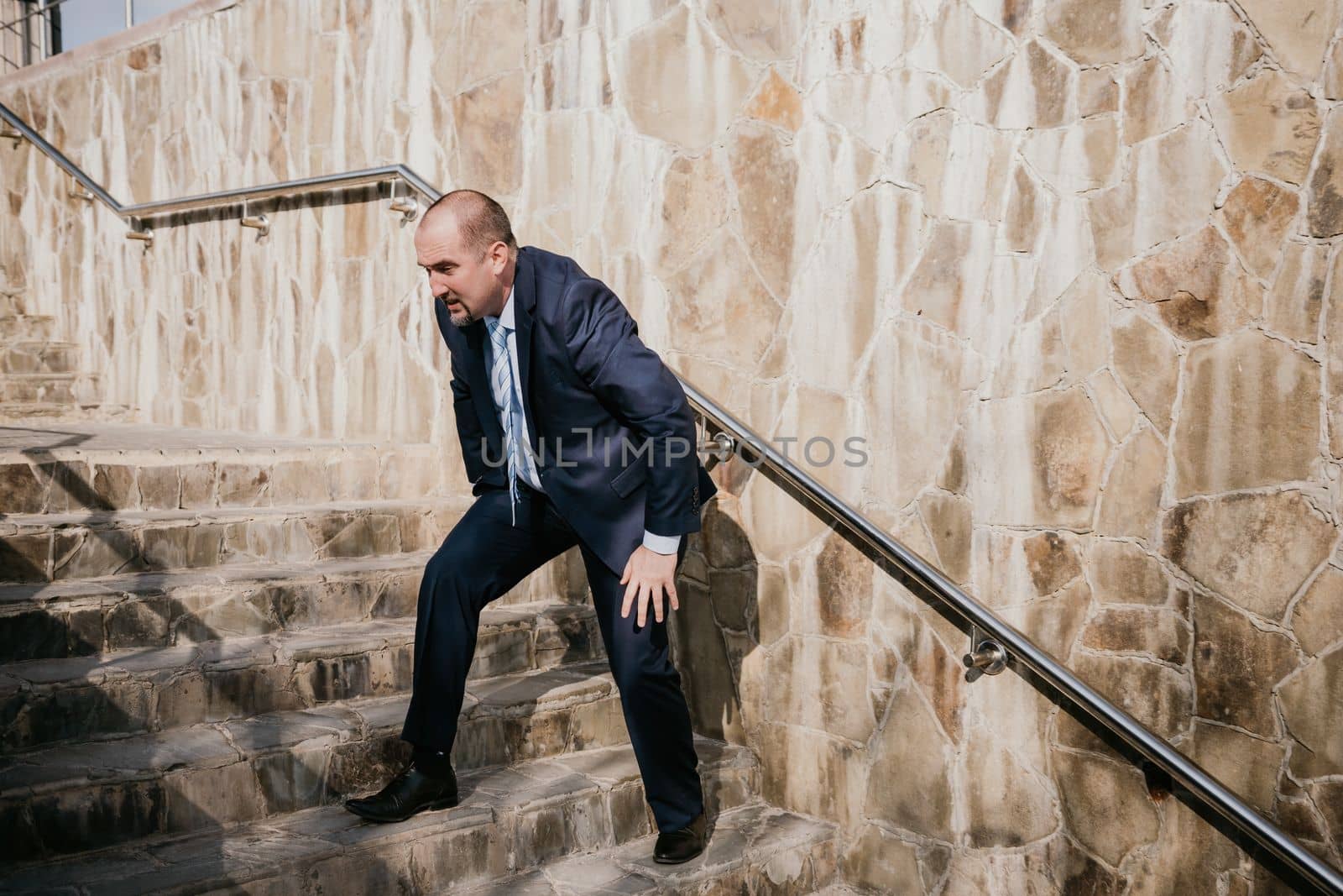 Portrait of a senior professional man in a suit with various problems. A middle-aged businessman with a briefcase descends the stairs.