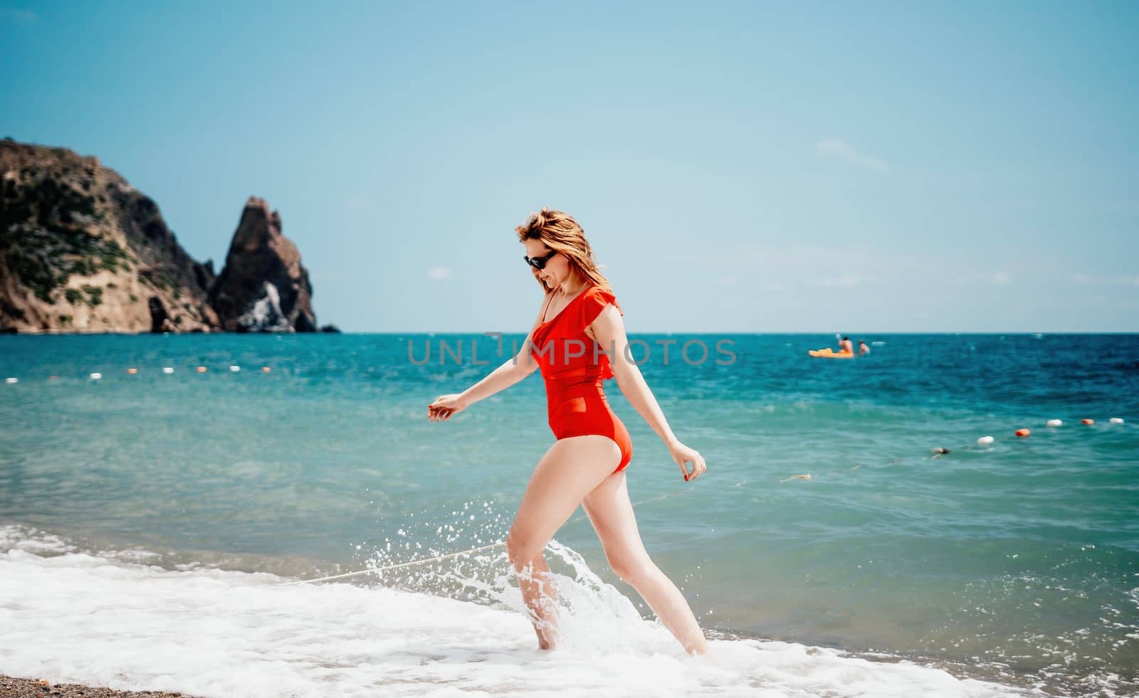 Young happy woman walks carefree on the seaside. Happy lady in red bikini. Portrait beautiful young woman relax smile around beach sea ocean in holiday vacation travel trip.