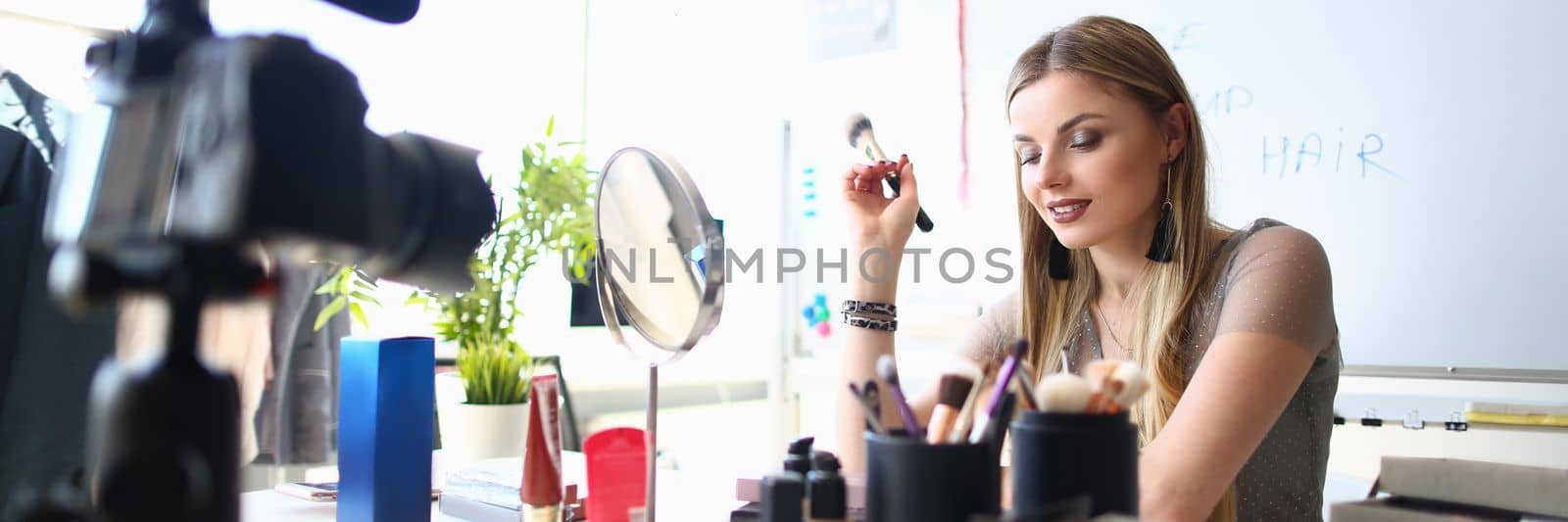 Young female blogger is recording tutorial video for blog about cosmetics. Maintaining an online blog and video blog about makeup and cosmetics