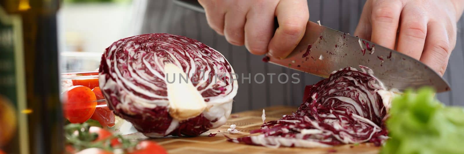 Cutting red cabbage with knife on cutting board in kitchen by kuprevich