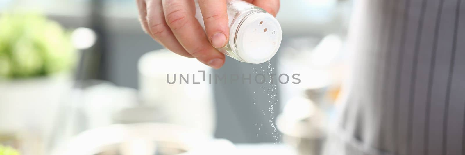 Chef salting boiling water or foods in saucepan by kuprevich