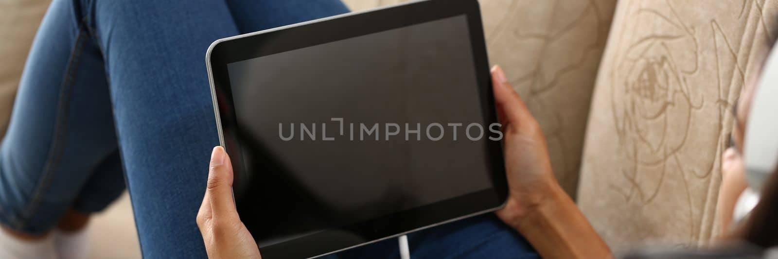 Woman using mobile app on digital tablet over shoulder view. Viewing information and communicating in social networks on Internet