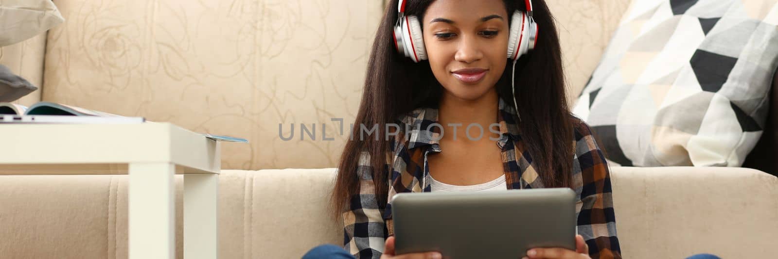 Learn foreign language online at home through application. Focused mixed race woman and remote female student sitting on floor in headset holding tablet pc