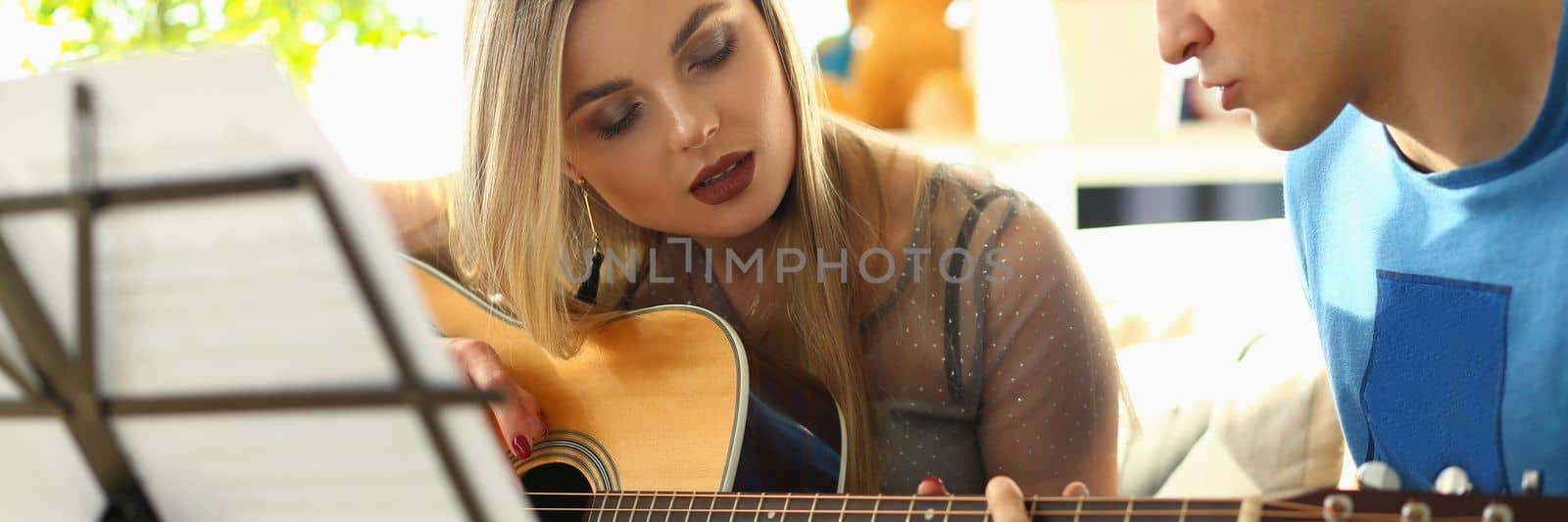 Man conducts guitar lessons for woman. Extracurricular tutoring hobby or creative music lessons