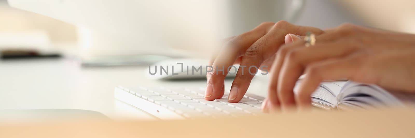 Closeup of female hands typing on keyboard and diary. Remote learning work and search for information on Internet