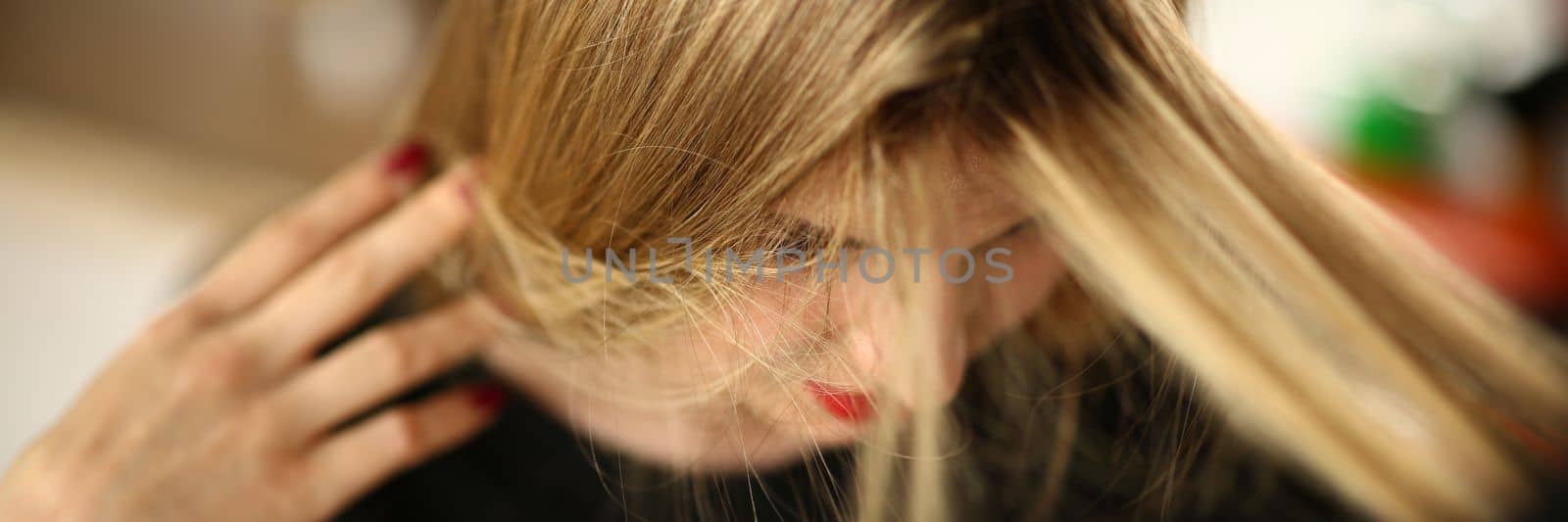 Young blonde woman demonstrates regrown hair roots. Closeup of woman head and long hair