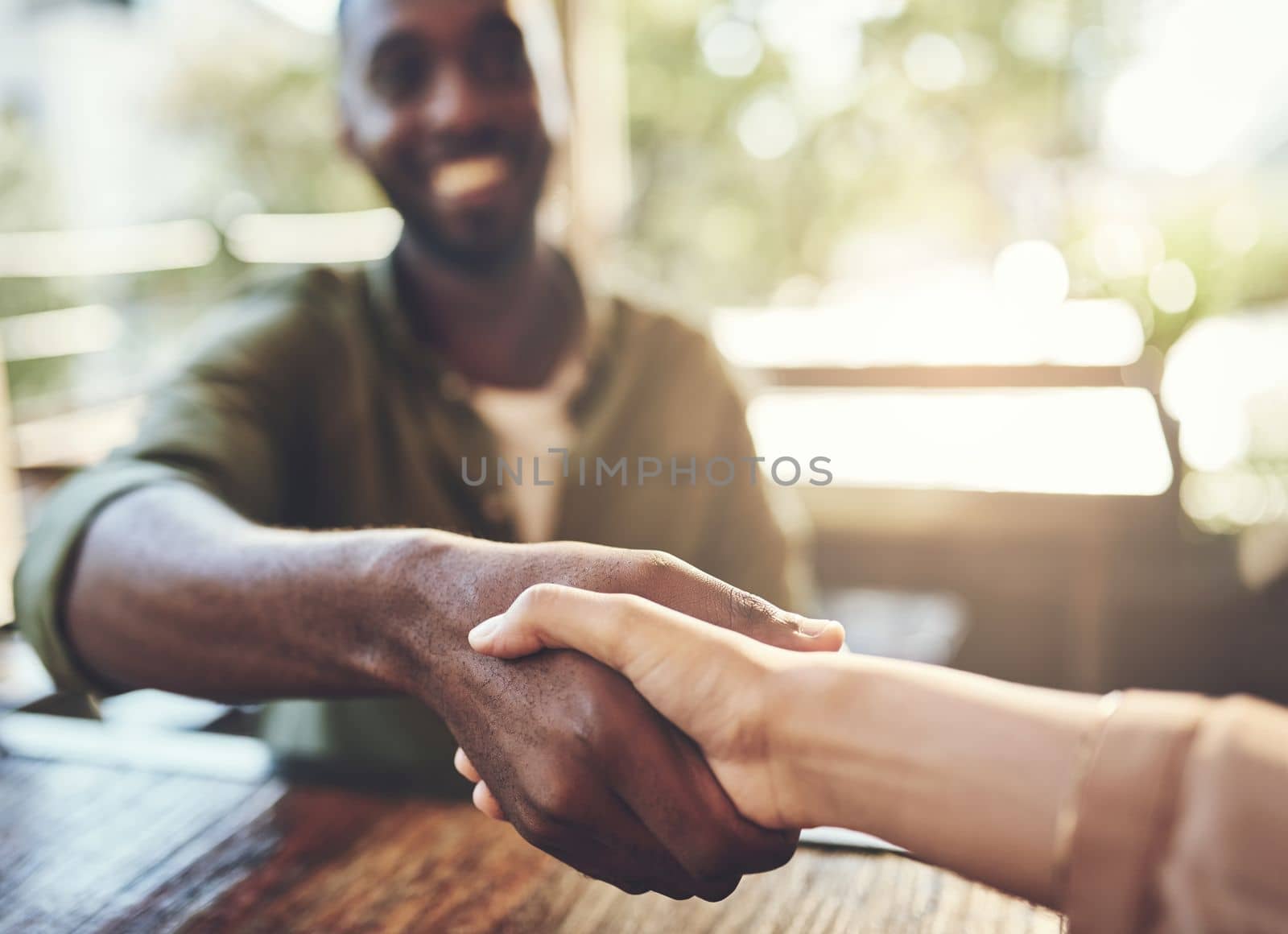 Connect with new people wherever you are. two people shaking hands in a cafe. by YuriArcurs