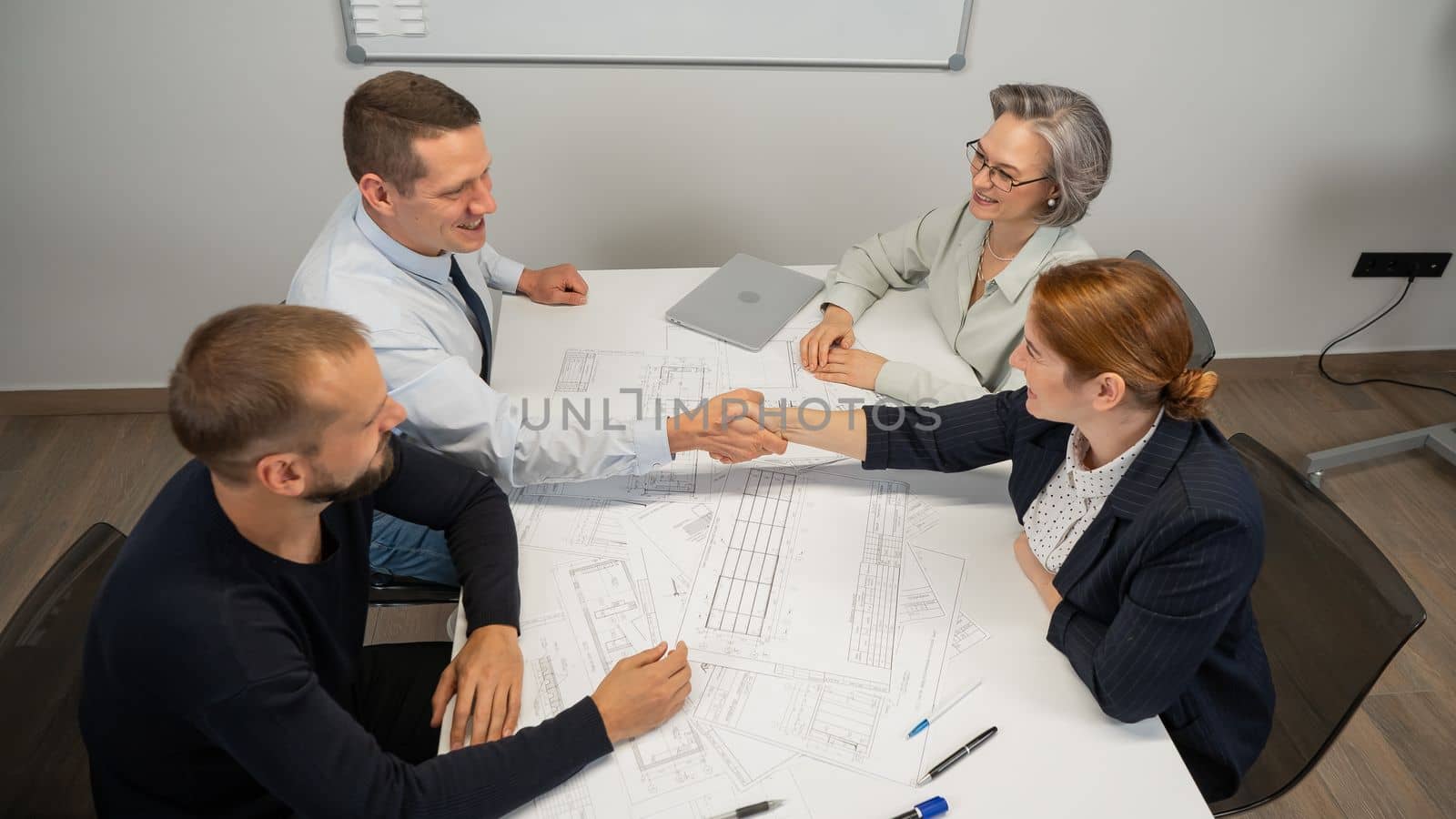 Business partners shake hands. Four business people are negotiating in the conference room