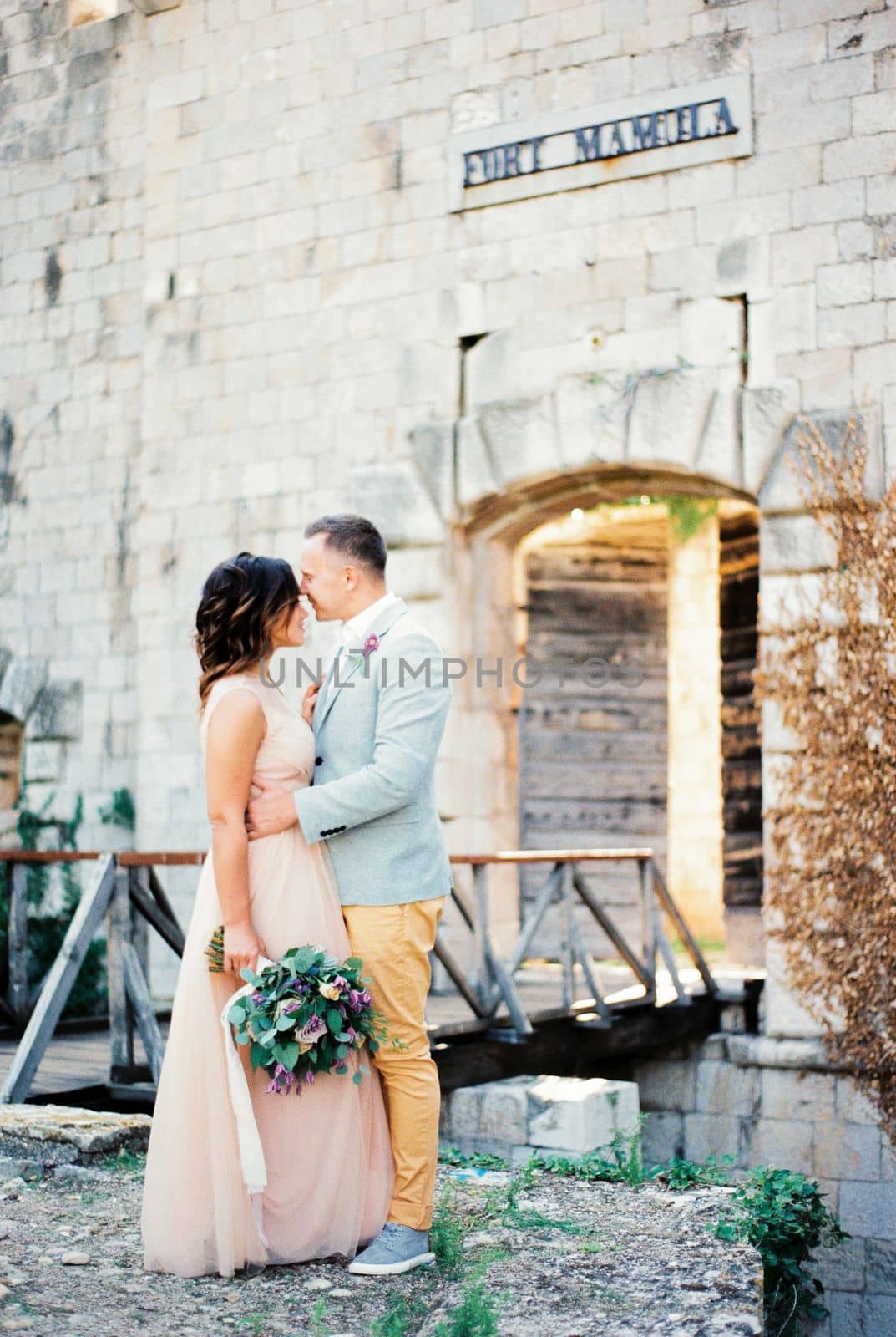 Groom hugs the bride near the bridge to Mamula Fort. High quality photo