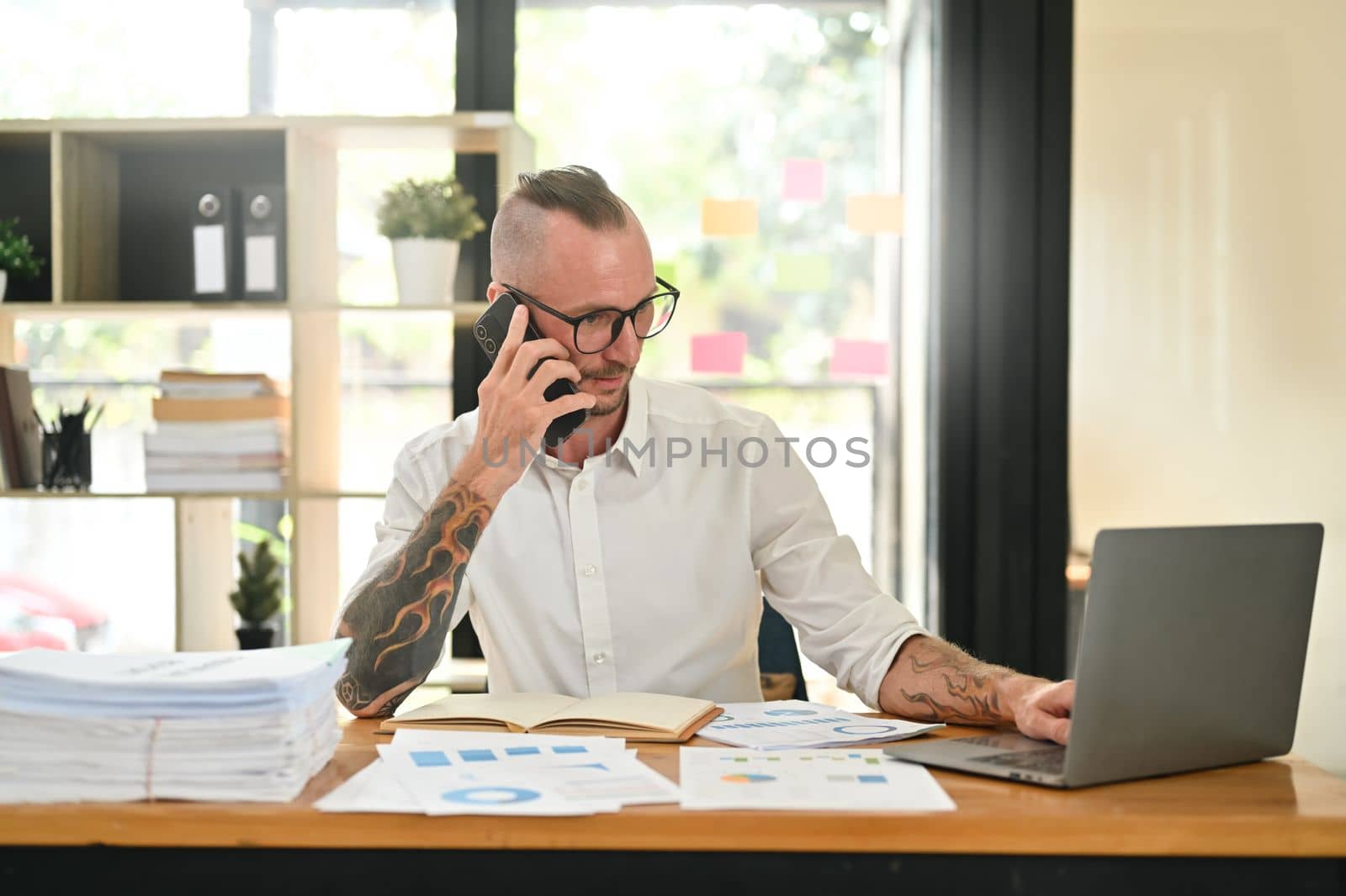 Positive male investment advisor answering or giving consultation to customer on mobile phone.
