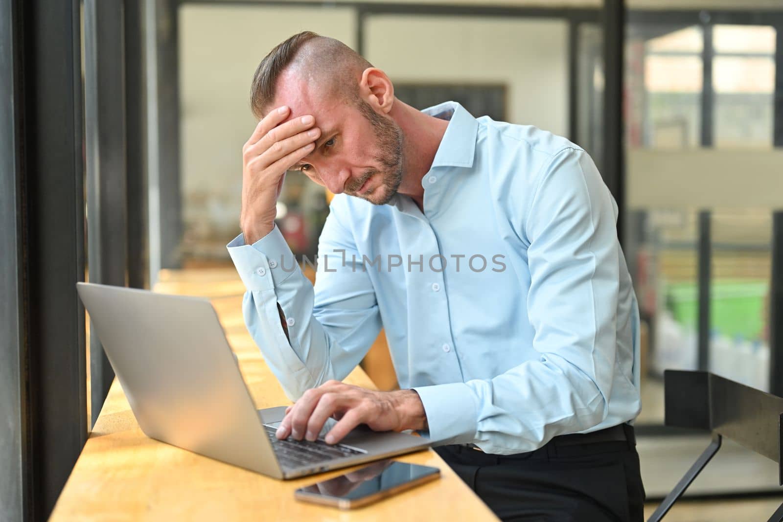 Overworked caucasian man office worker holding her head in hands, feeling distressed anxious with work deadline.