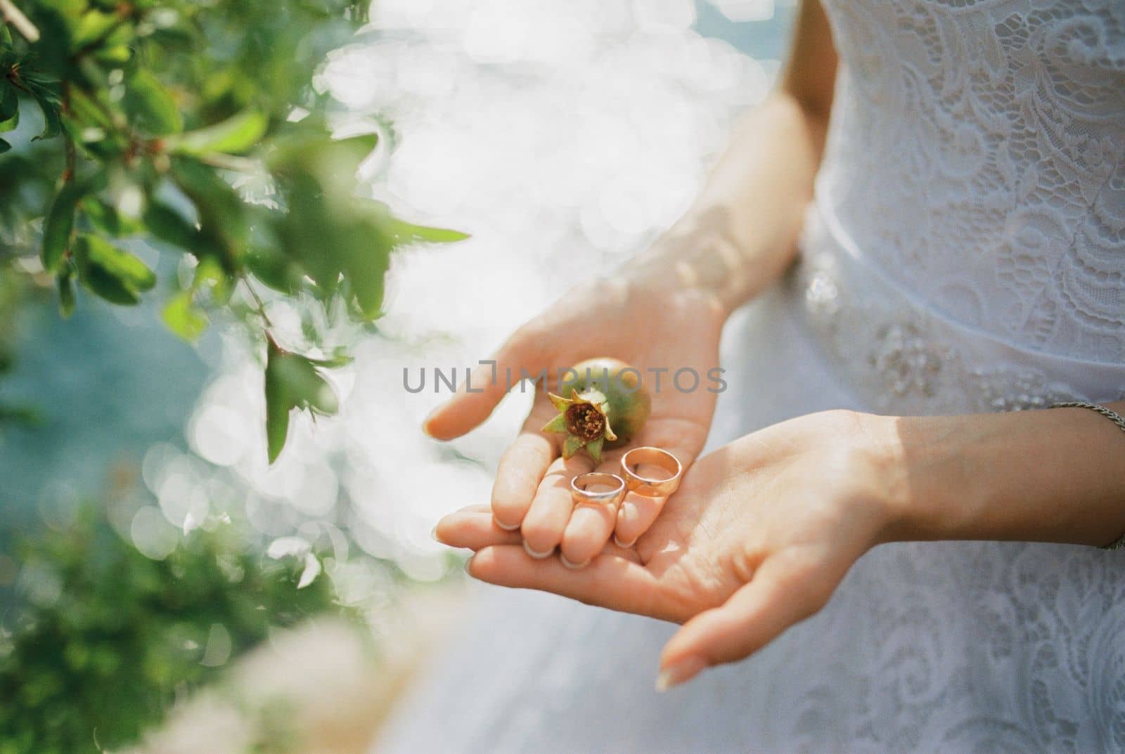 Wedding rings with a small pomegranate lie on the palms of the bride. High quality photo