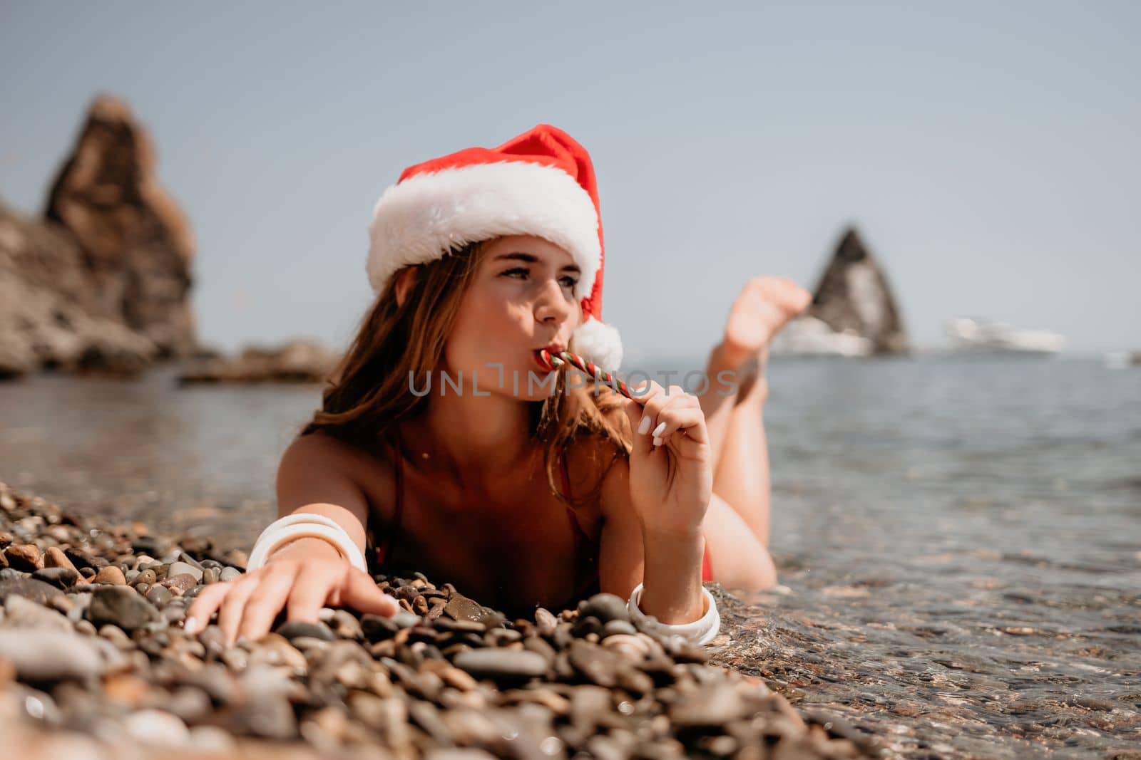 Woman travel sea. Happy tourist enjoy taking picture on the beach for memories. Woman traveler in Santa hat looks at camera on the sea bay, sharing travel adventure journey by panophotograph