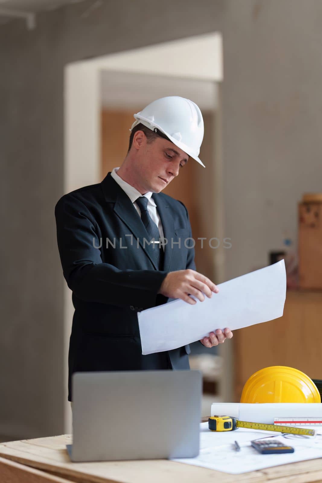 Portrait American professional Engineer or Civil. Engineering worker wear safety hardhat. architectural plan, engineer sketching a construction concept. by itchaznong