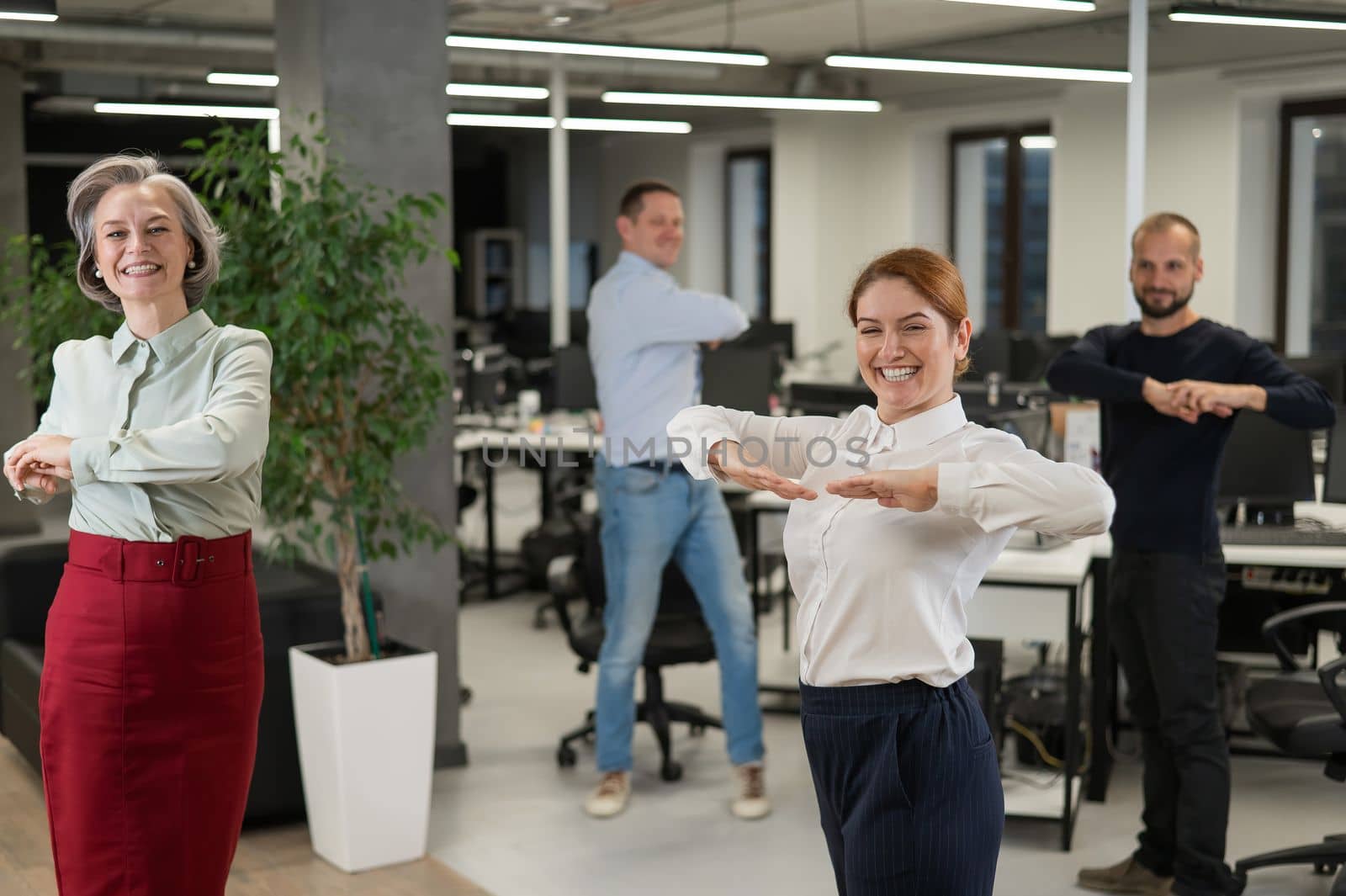 Four office workers warm up during a break. Employees do fitness exercises at the workplace. by mrwed54