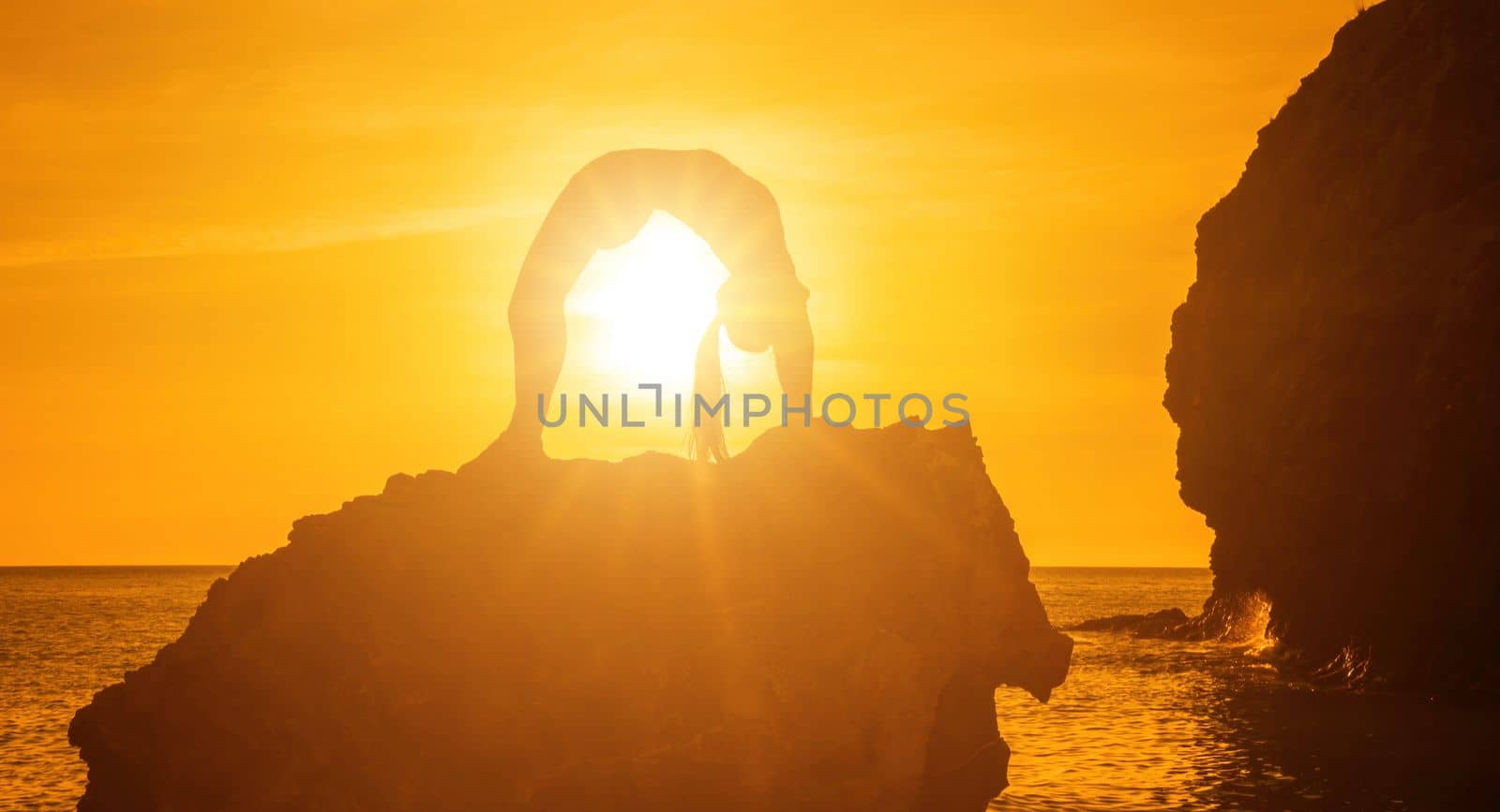 Young woman with black hair, fitness instructor in pink sports leggings and tops, doing pilates on yoga mat with magic pilates ring by the sea on the beach. Female fitness daily yoga concept