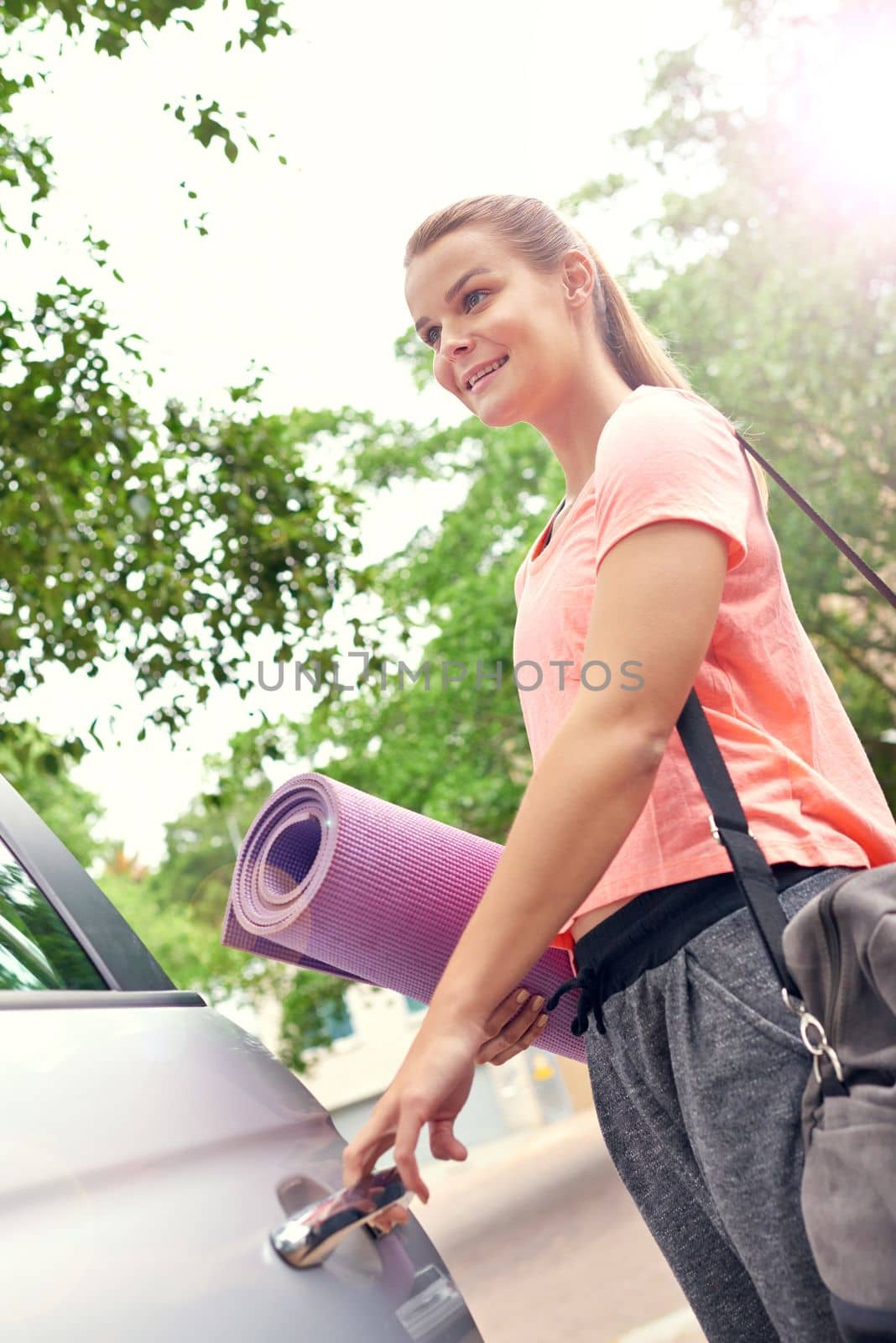 This yoga session is just what I need. a beautiful young woman carrying a yoga mat while getting into her car. by YuriArcurs
