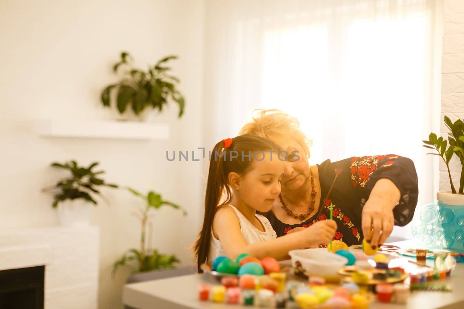 grandmother with granddaughter play with easter eggs, easter time to paint eggs. by Andelov13