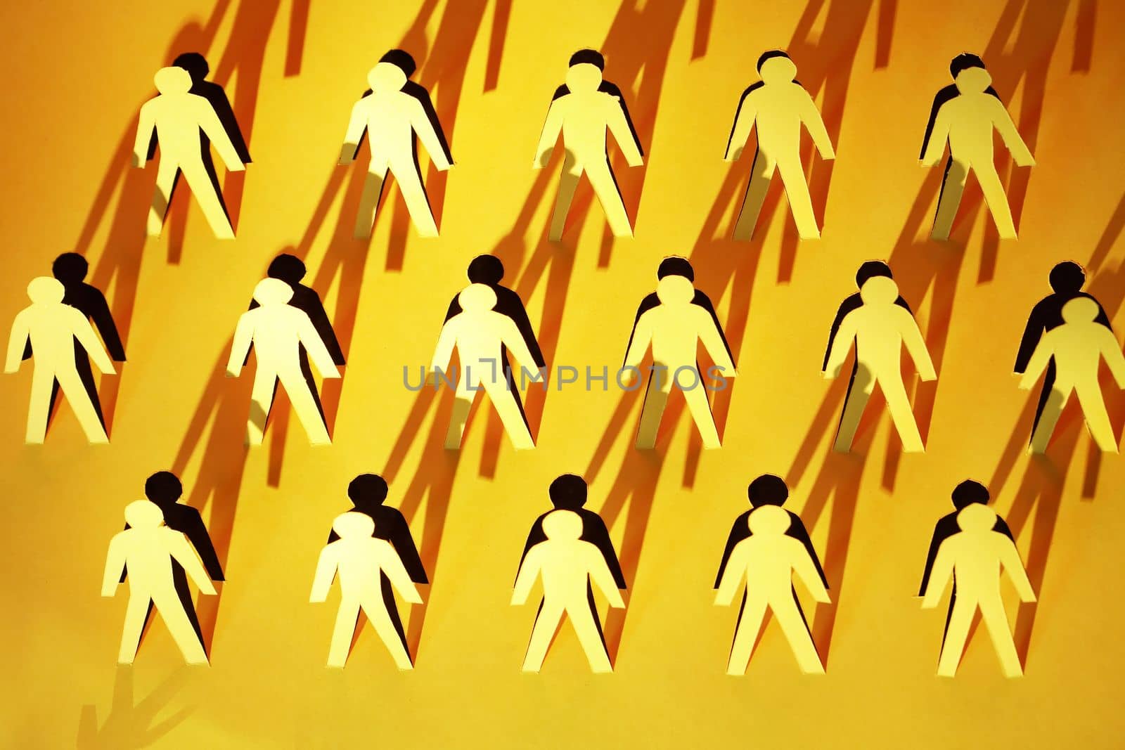 Lot of men figures cutting from yellow paper with long shadow