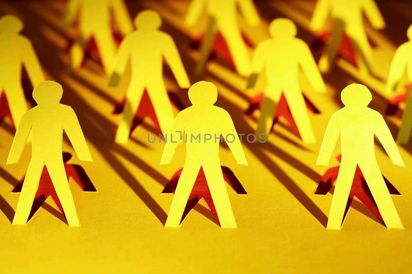 Lot of men figures cutting from yellow paper with long shadow