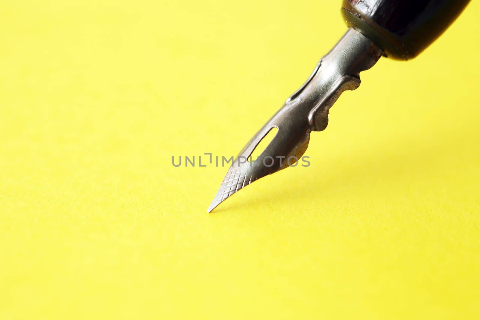 Closeup of nice vintage ink pen on empty yellow paper