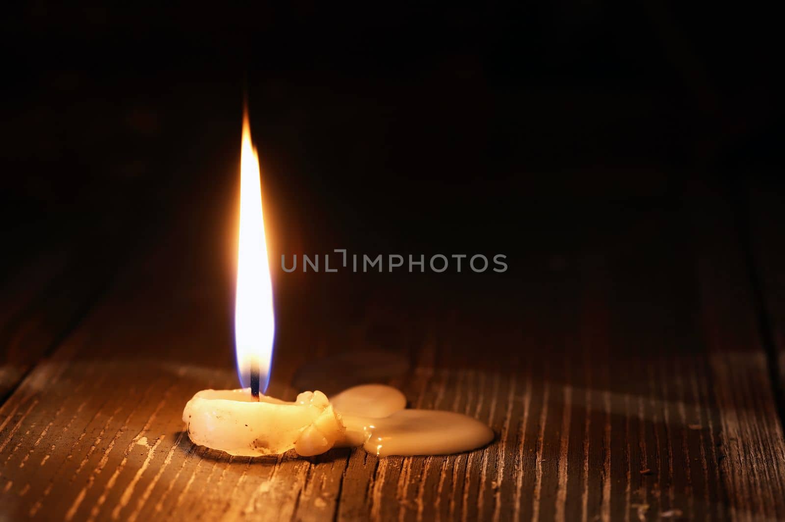 Alone lighting candle on old wooden surface
