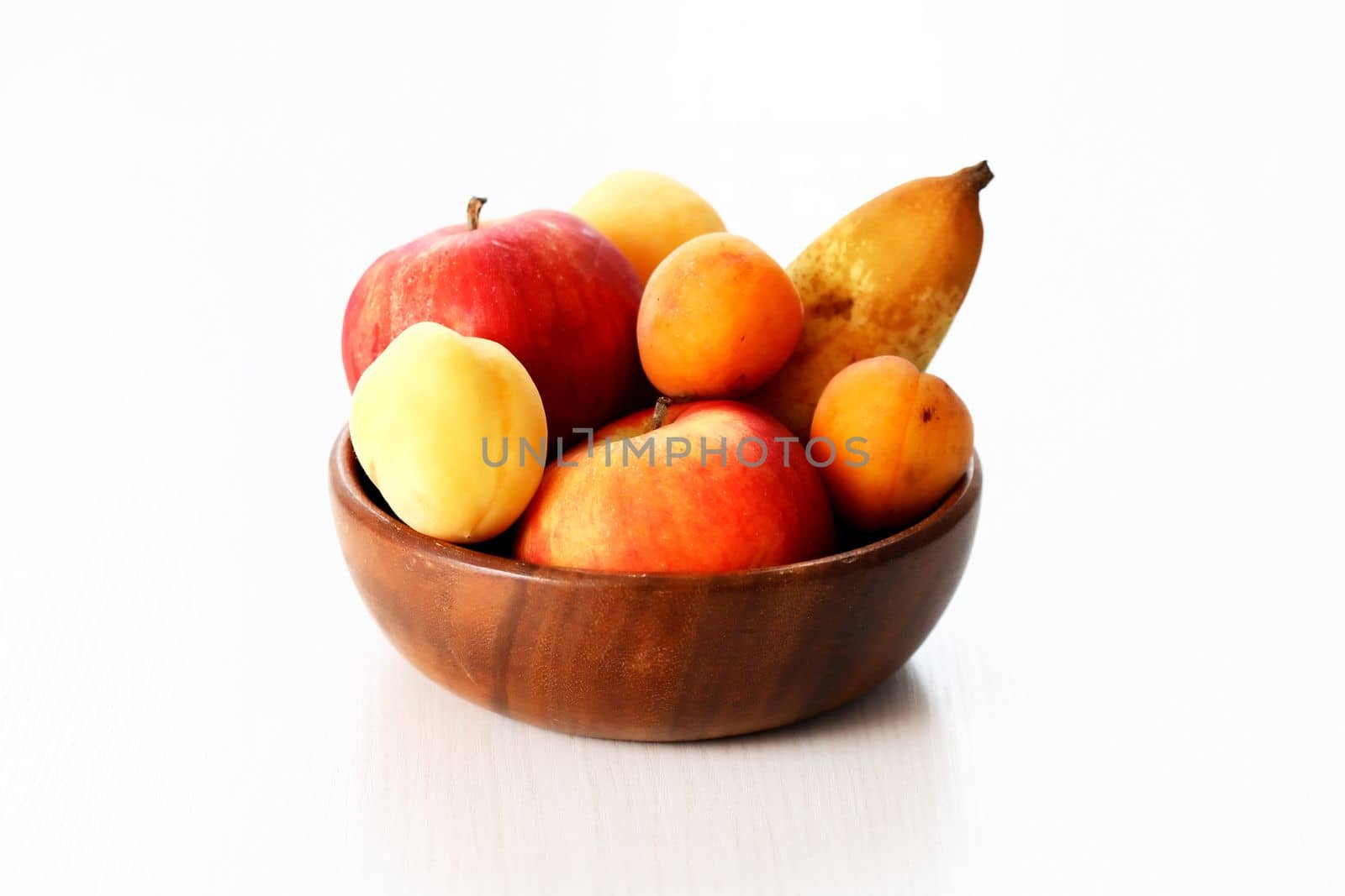 Heap of freshness fruits in wooden bowl on white background