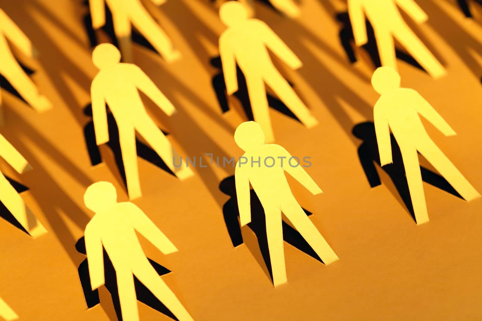 Lot of men figures cutting from yellow paper with long shadow