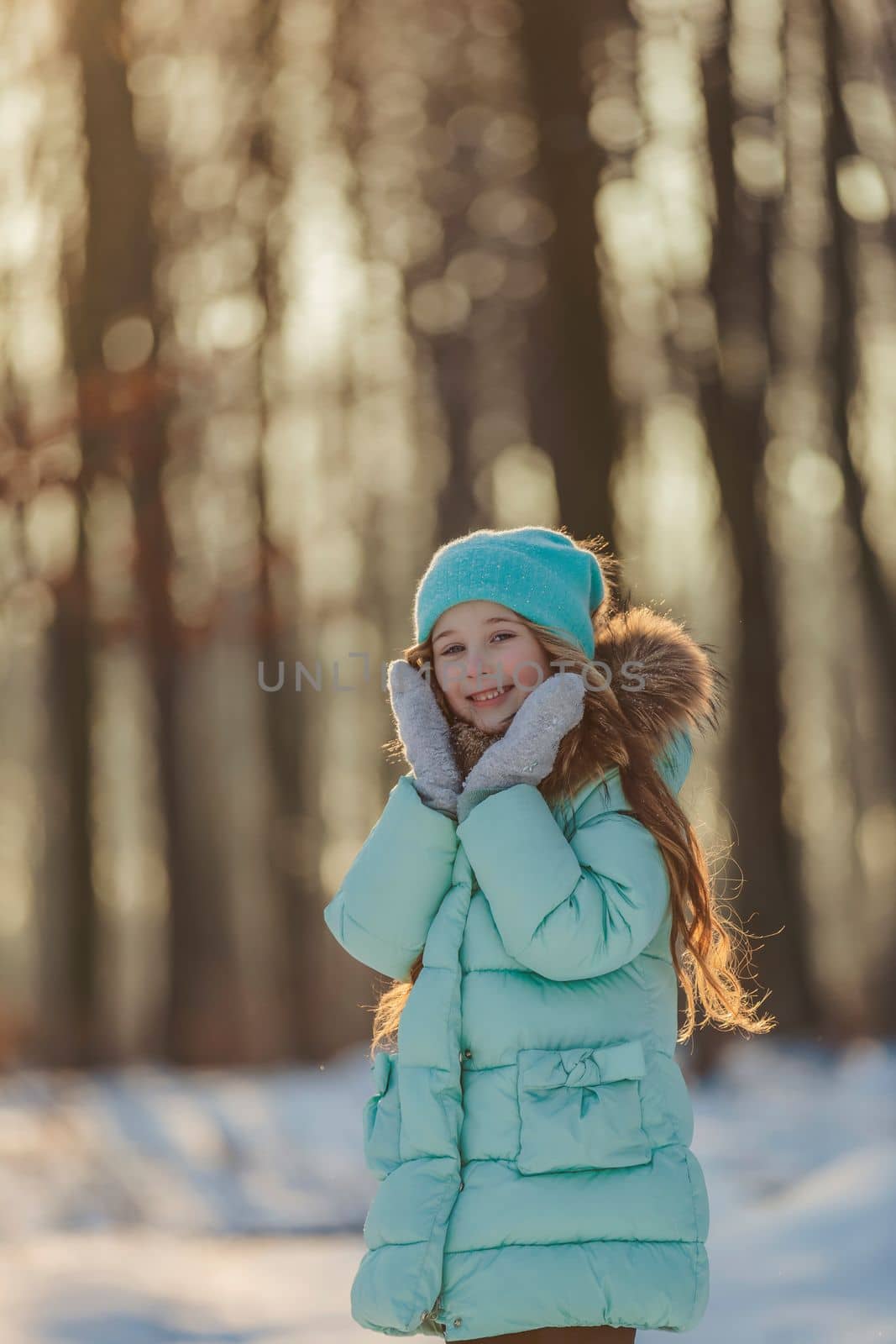 girl in a turquoise squat and a hat in the winter forest by zokov