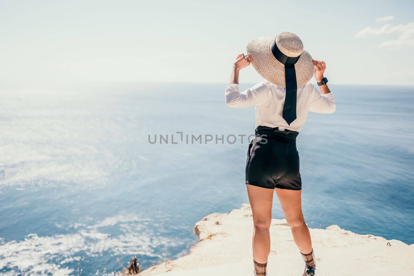 Woman sea hat. Business woman in yellow hat freelancer working over blue sea beach. Girl relieves stress from work. Freelance, digital nomad, travel and holidays concept by panophotograph