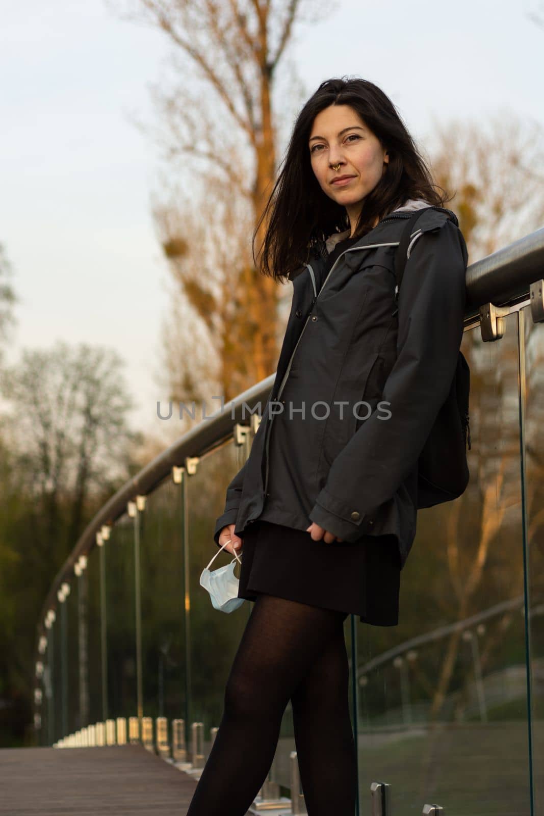 Portrait of happy young woman without protective face medical mask standing in park at sunset during spring. High quality photo