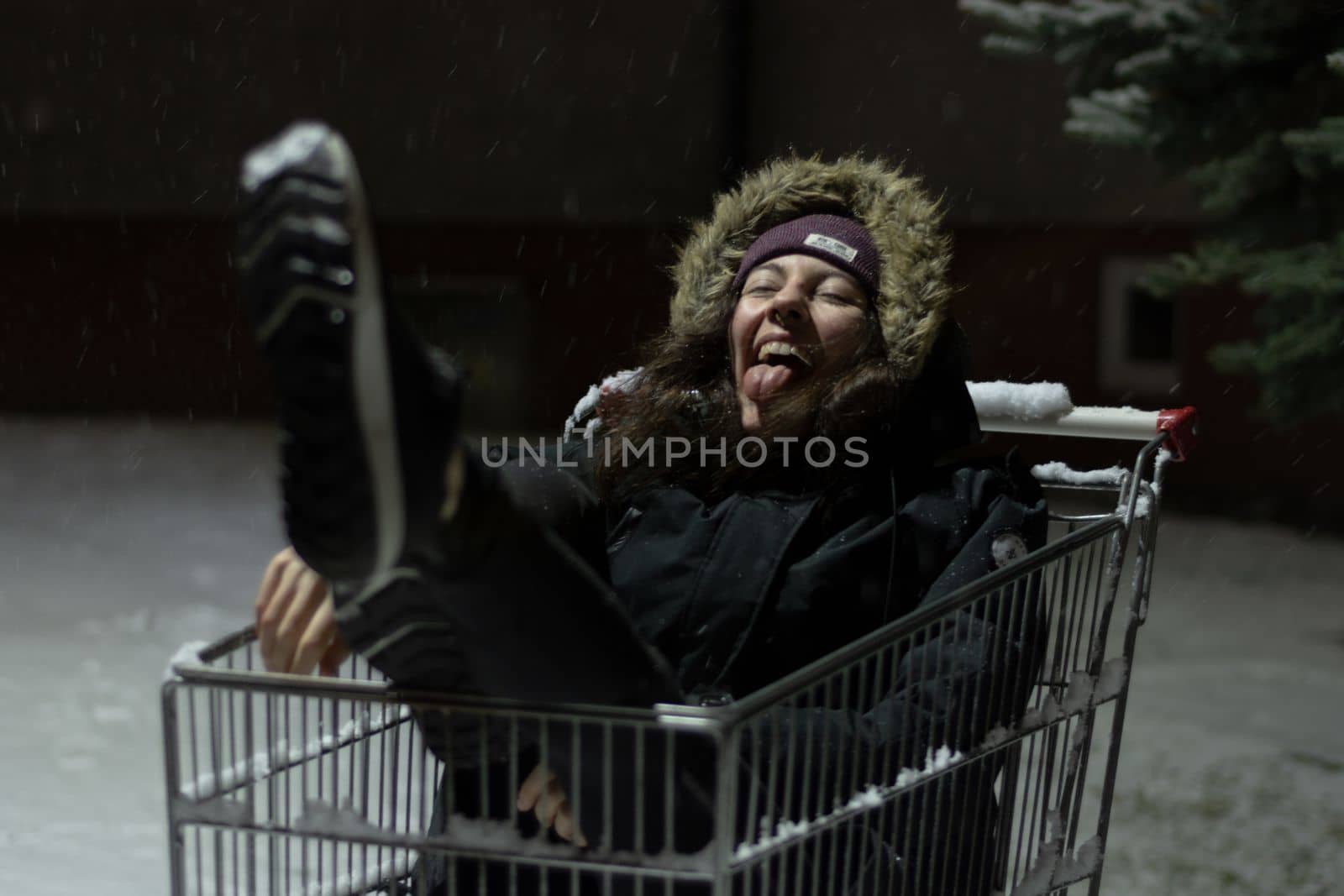 Happy young woman inside a shopping cart during a winter snow storm by scasal15