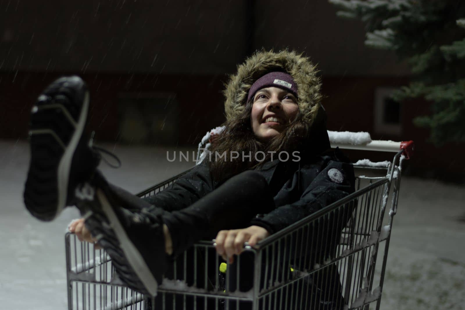 Happy young woman inside a shopping cart during a winter snow storm by scasal15