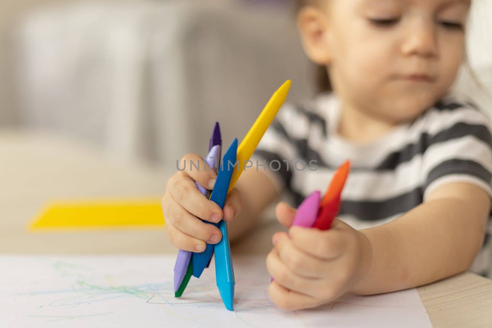 cute caucasian baby girl drawing greeting card for mothers day. Image with selective focus on hand