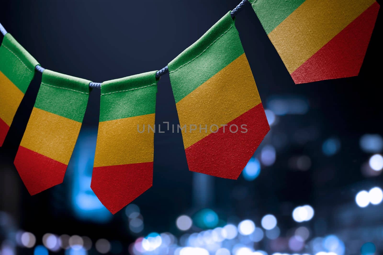 A garland of Mali national flags on an abstract blurred background.
