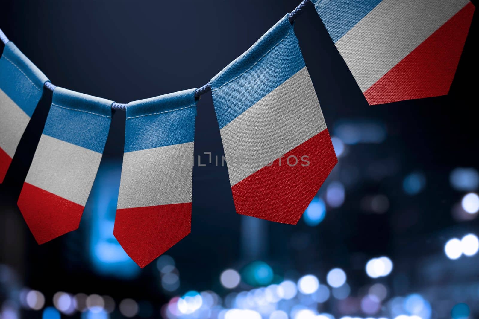 A garland of France national flags on an abstract blurred background.