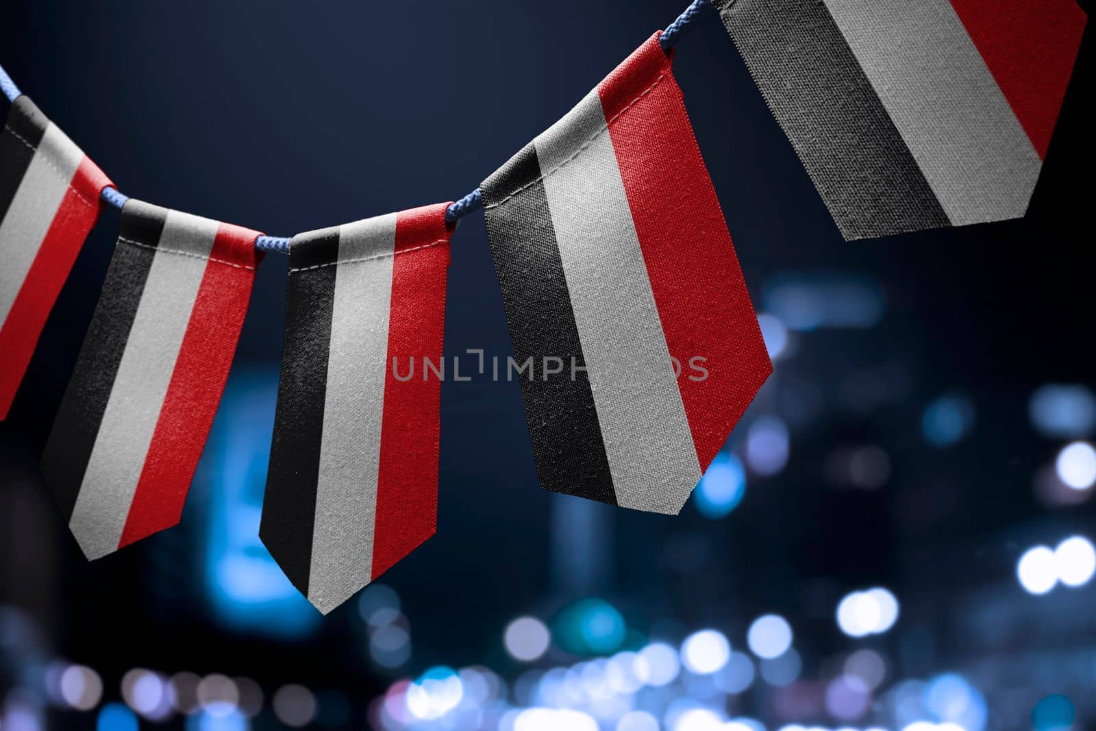 A garland of Yemen national flags on an abstract blurred background.
