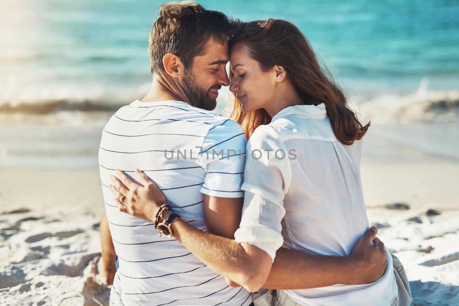 Summer romance doesnt get any better than this. Rearview shot of a young couple kissing on a summers day at the beach