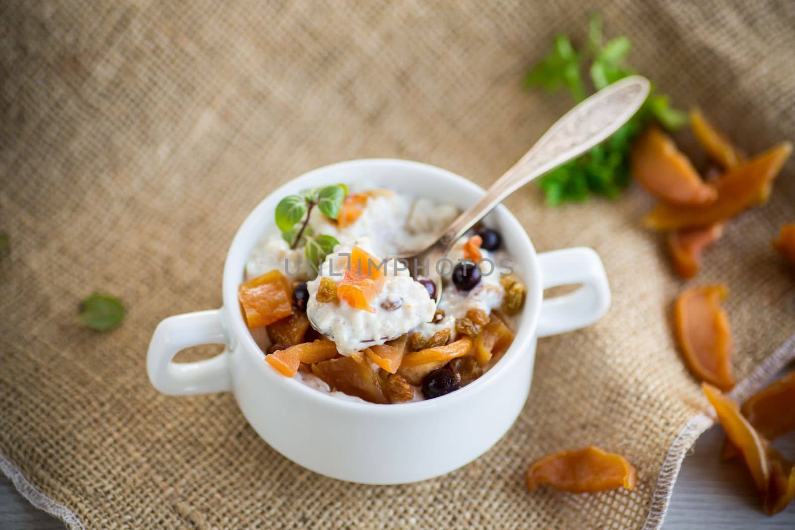 oatmeal with candied fruits, raisins in a plate on a burlap tablecloth