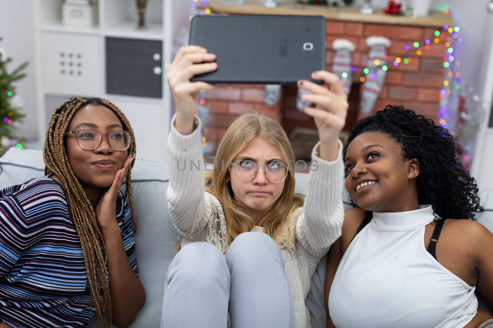 Crazy tablet photos of three friends right by the fireplace. Christmas decoration of the living room. Sudeten friendships.