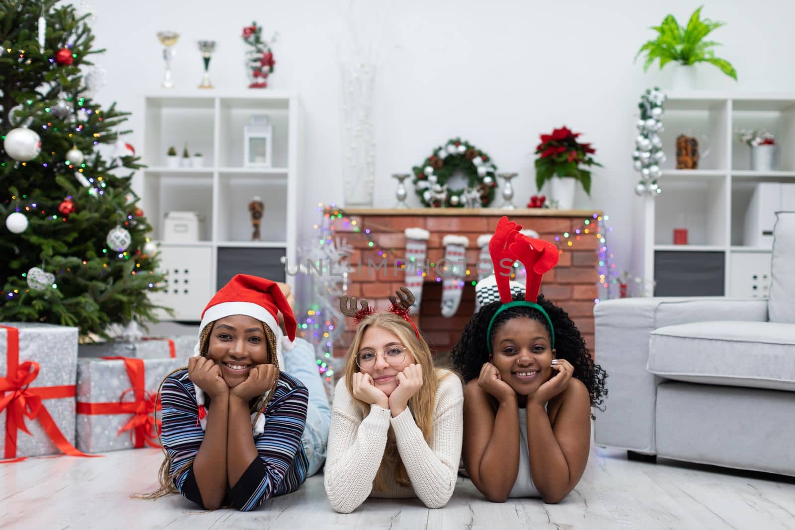 Smiling virgins lie on the floor and look straight into the camera. Christmas spent among friends from Africa and Europe. Christmas decoration.