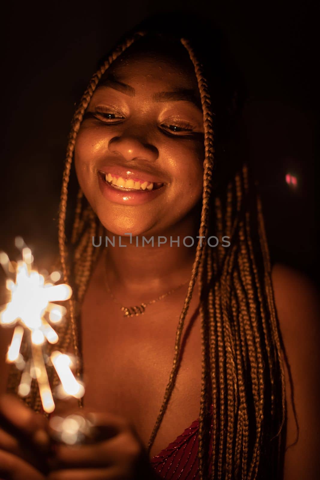 Cold fireworks during New Year's celebrations. A smiling dark-skinned woman holds a burning firework in her hand.