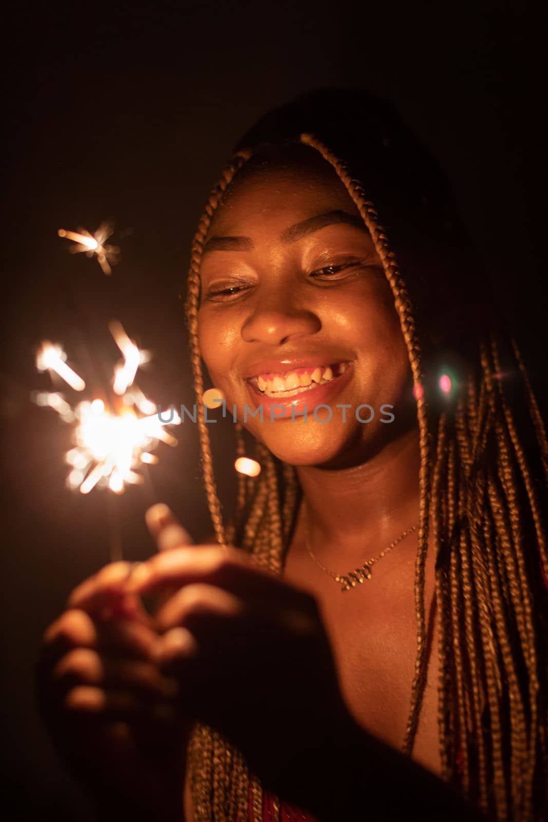 New Year's Eve fun with cold fires. An African woman and her wonderful smile. Happiness and joy is drawn on the young girl's face.